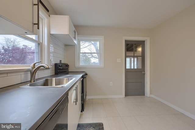 kitchen featuring tasteful backsplash, stainless steel dishwasher, sink, white cabinets, and black / electric stove