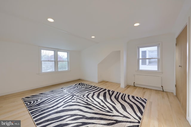 bonus room featuring lofted ceiling, a healthy amount of sunlight, light wood-type flooring, and radiator heating unit