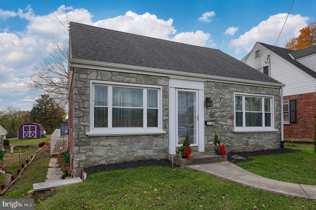 view of front of house featuring a front yard and a storage shed