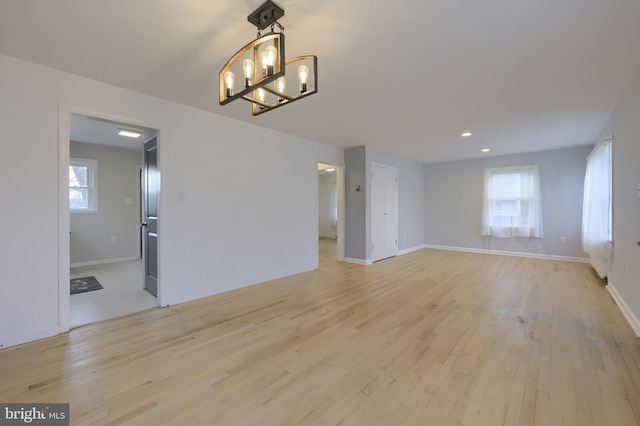 spare room with an inviting chandelier and light hardwood / wood-style flooring