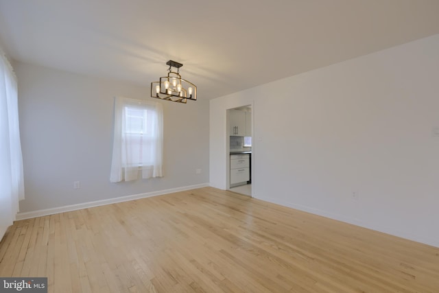 unfurnished room with an inviting chandelier and light wood-type flooring