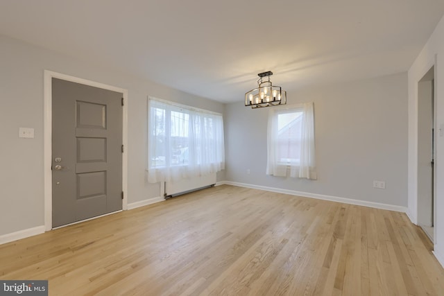 unfurnished dining area featuring light hardwood / wood-style floors and an inviting chandelier