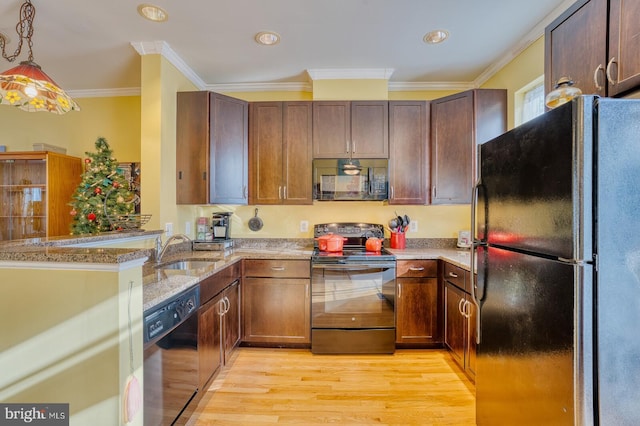 kitchen with pendant lighting, black appliances, crown molding, sink, and light wood-type flooring