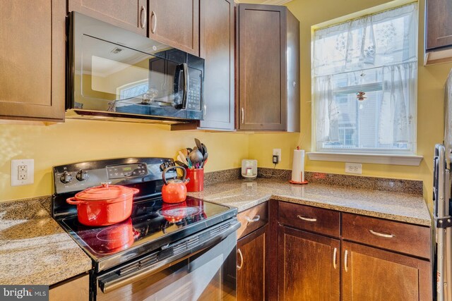 kitchen featuring light stone countertops, black appliances, and ornamental molding