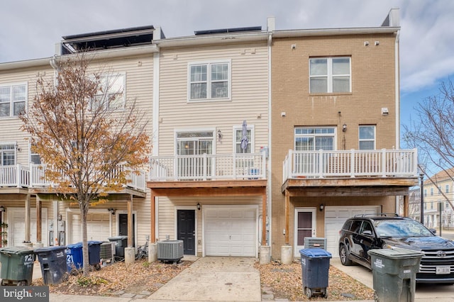 rear view of property featuring a garage and central AC