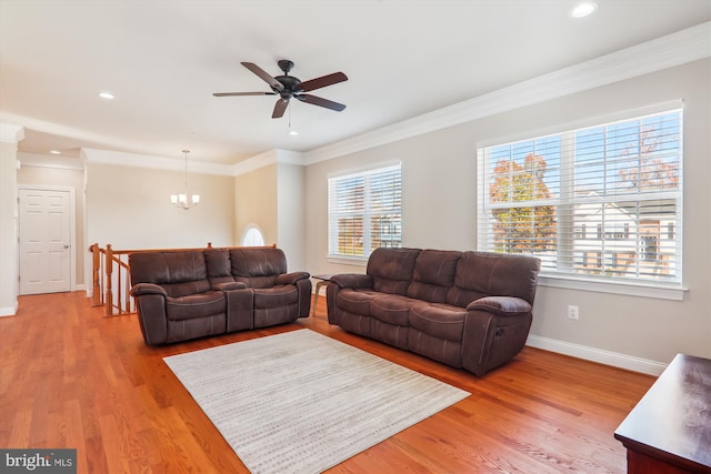 living room featuring crown molding, light hardwood / wood-style flooring, a healthy amount of sunlight, and ceiling fan with notable chandelier