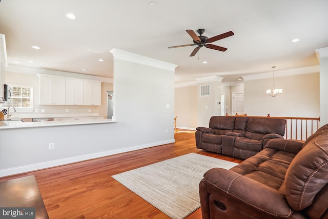 living room featuring ceiling fan with notable chandelier, light wood-type flooring, crown molding, and sink