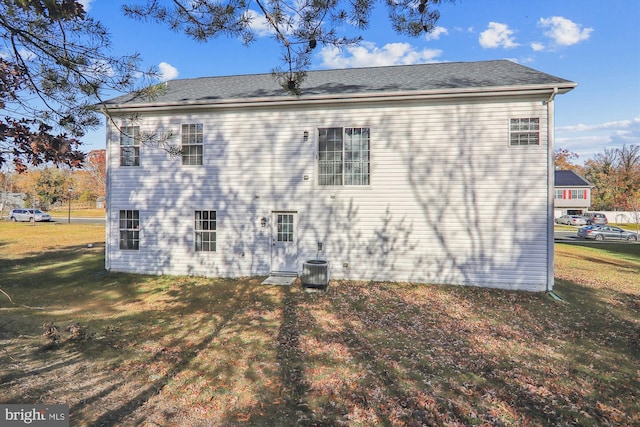 rear view of house featuring a lawn and cooling unit