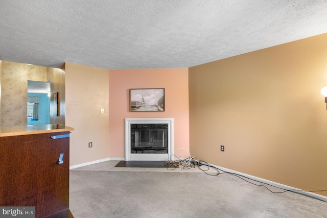 unfurnished living room featuring carpet floors, a fireplace with flush hearth, baseboards, and a textured ceiling