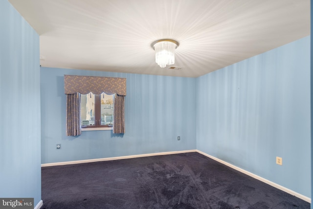 carpeted empty room featuring an inviting chandelier