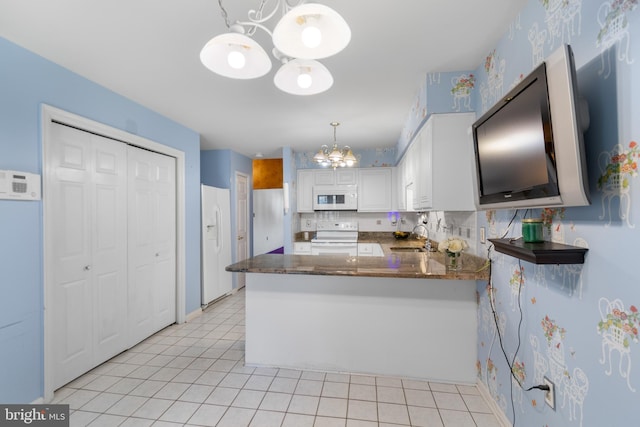 kitchen with a chandelier, white appliances, a peninsula, a sink, and white cabinets