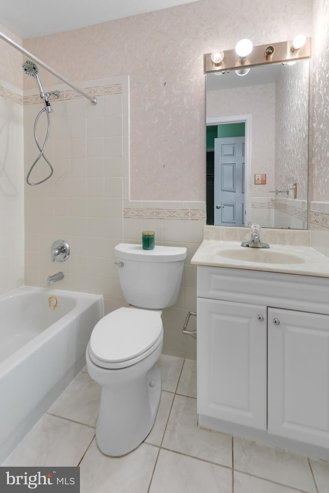 full bathroom with vanity, tiled shower / bath combo, tile walls, tile patterned flooring, and toilet