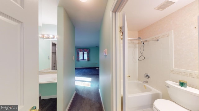 bathroom with tiled shower / bath combo and toilet