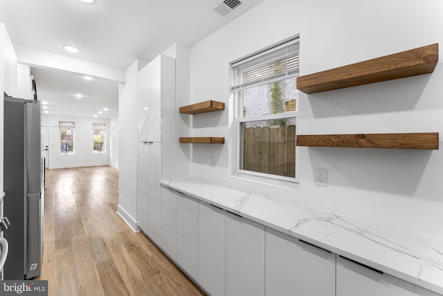 interior space featuring white cabinetry, light stone counters, and light hardwood / wood-style floors