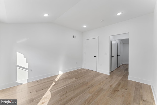 unfurnished room with light wood-type flooring and lofted ceiling