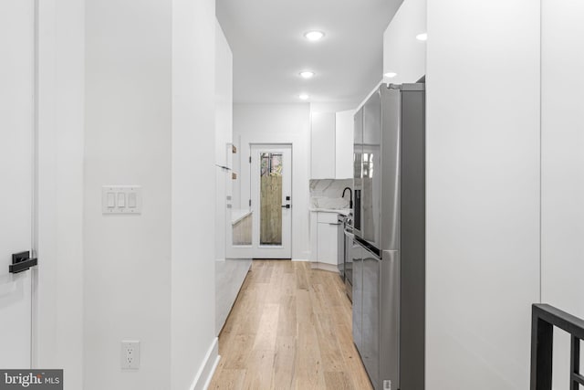 kitchen with white cabinetry, light wood-type flooring, tasteful backsplash, and stainless steel fridge with ice dispenser