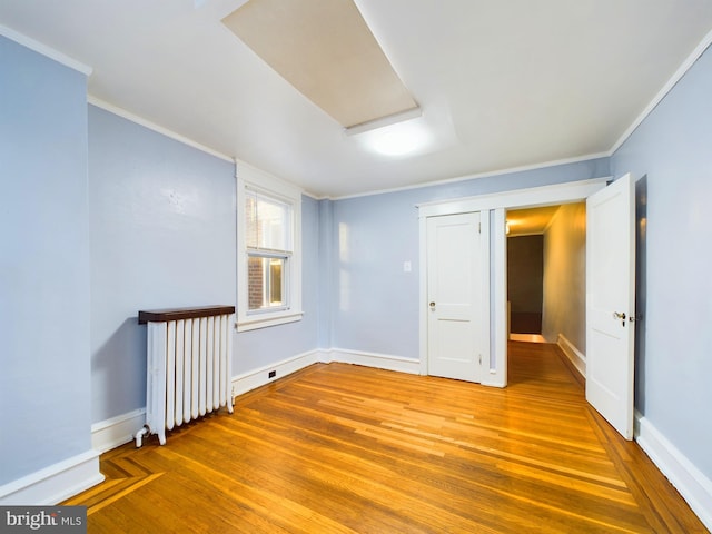 spare room with hardwood / wood-style floors, radiator heating unit, and crown molding