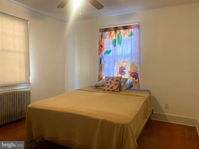 bedroom with dark hardwood / wood-style flooring, radiator heating unit, and ceiling fan