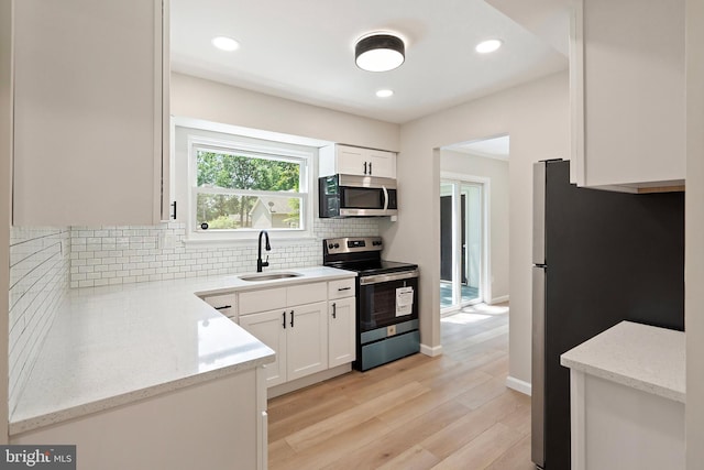 kitchen with white cabinetry, sink, light wood-type flooring, and appliances with stainless steel finishes