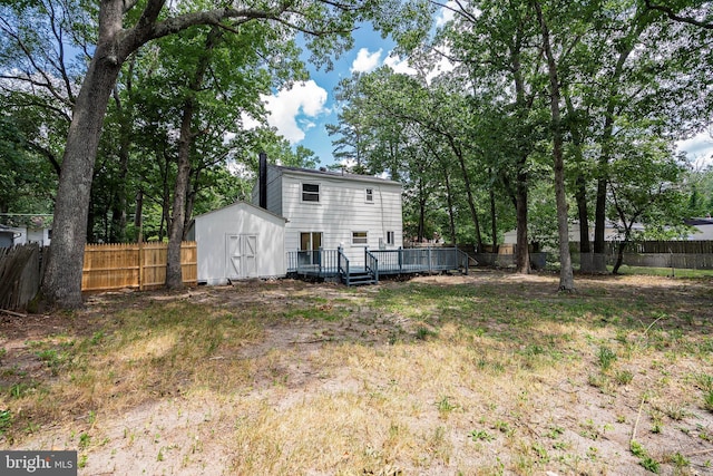 rear view of property featuring a shed and a wooden deck