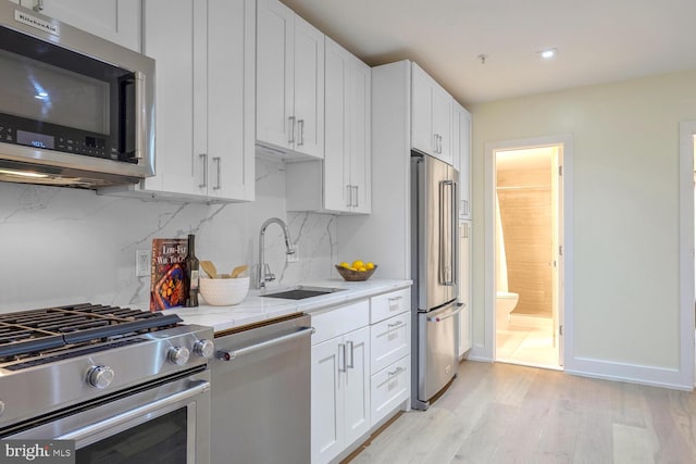 kitchen featuring white cabinetry, sink, light hardwood / wood-style flooring, and high end appliances