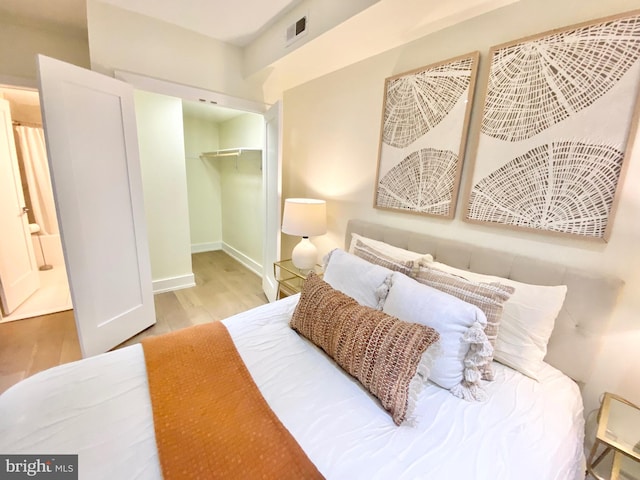 bedroom featuring a closet, light hardwood / wood-style flooring, and a spacious closet