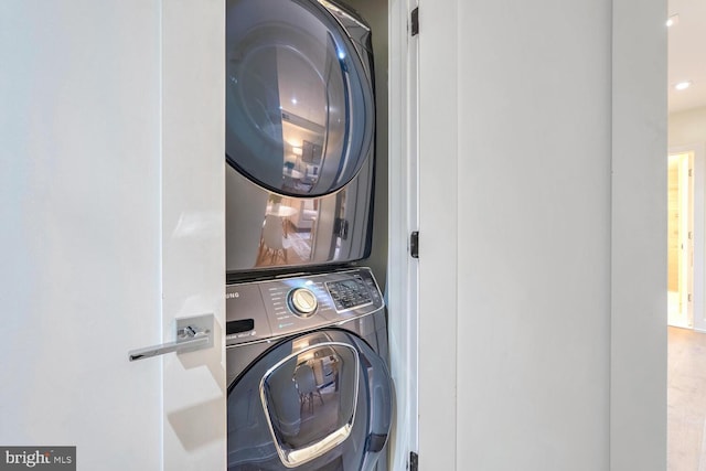 clothes washing area with hardwood / wood-style floors and stacked washing maching and dryer