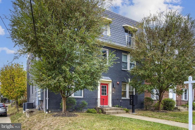 view of front of home with a front yard and central AC