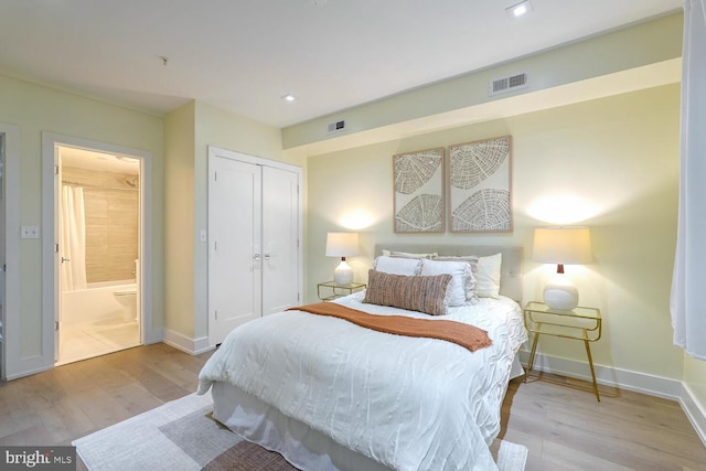 bedroom with ensuite bath, light wood-type flooring, and a closet