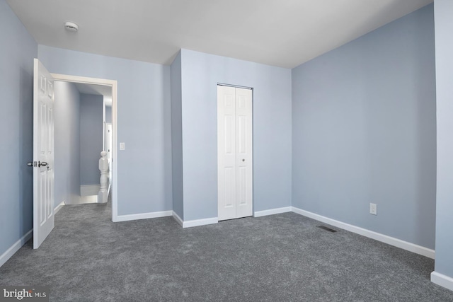 unfurnished bedroom featuring a closet and dark colored carpet