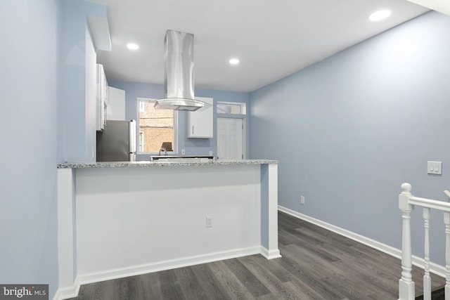 kitchen featuring dark hardwood / wood-style flooring, island exhaust hood, stainless steel refrigerator, and white cabinets