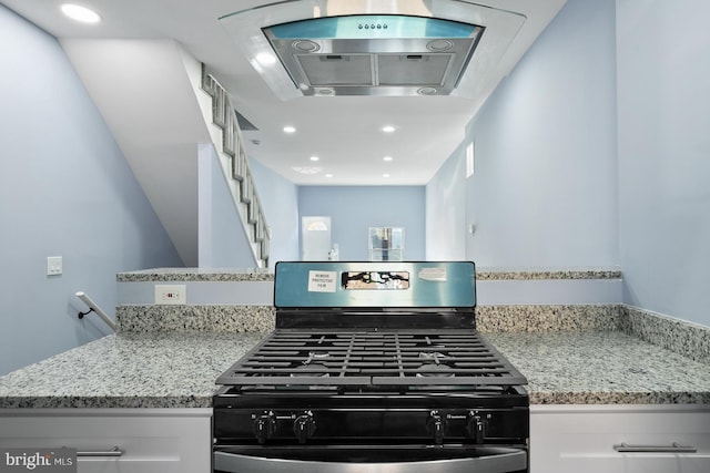 kitchen with gas stove, light stone counters, and white cabinets