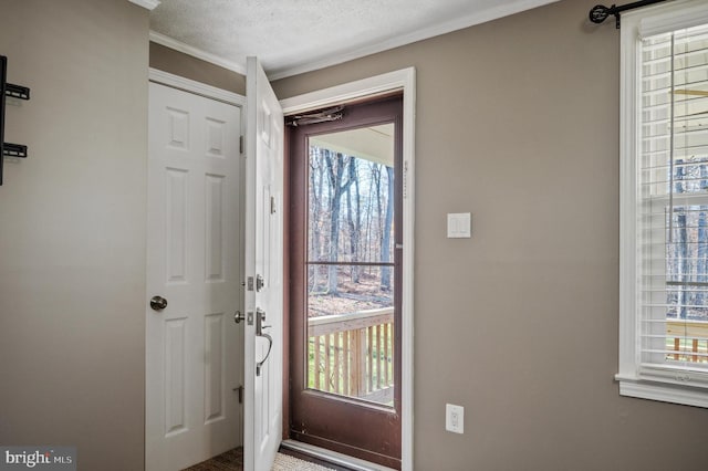 doorway to outside featuring plenty of natural light, crown molding, and a textured ceiling