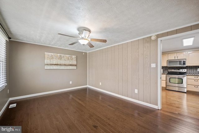 spare room with wood walls, dark hardwood / wood-style floors, ceiling fan, ornamental molding, and a textured ceiling