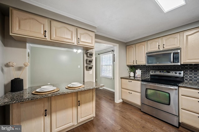 kitchen with dark wood-type flooring, decorative backsplash, dark stone countertops, ornamental molding, and appliances with stainless steel finishes