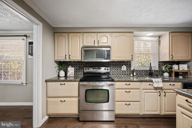 kitchen featuring dark wood-type flooring, stainless steel appliances, dark stone countertops, crown molding, and decorative backsplash