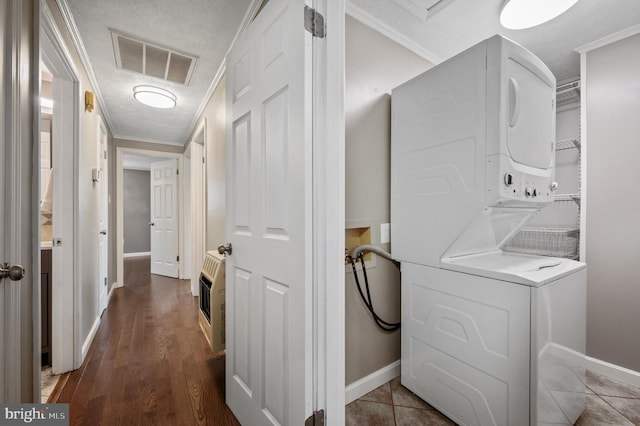 laundry area featuring crown molding, dark hardwood / wood-style floors, a textured ceiling, stacked washer / dryer, and heating unit