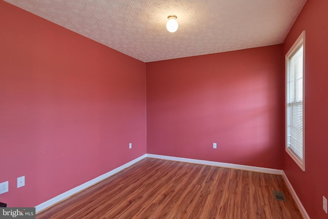 empty room with wood-type flooring and a textured ceiling