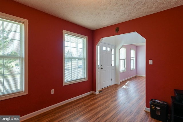 foyer entrance with a textured ceiling and dark wood-type flooring