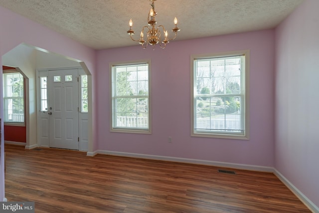 entrance foyer featuring dark hardwood / wood-style flooring, a textured ceiling, and a notable chandelier