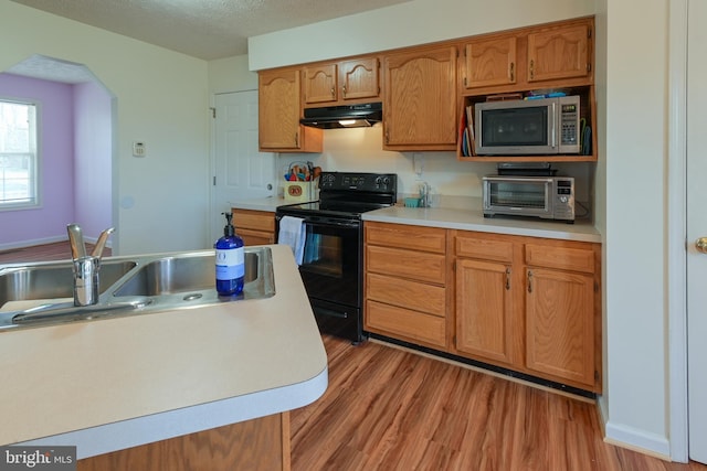 kitchen with a textured ceiling, black range with electric cooktop, light hardwood / wood-style floors, and sink