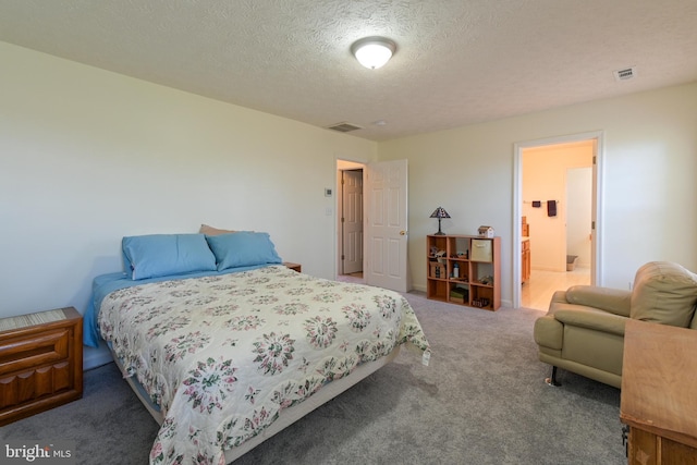 bedroom with connected bathroom, carpet, and a textured ceiling