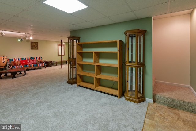 basement featuring a paneled ceiling and carpet