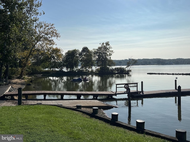 view of dock with a yard and a water view