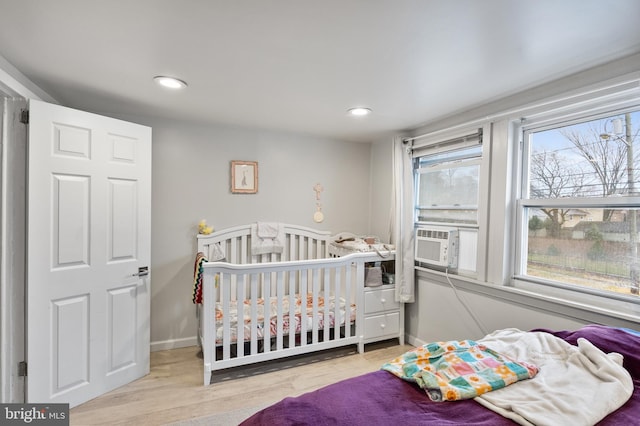 bedroom with cooling unit and light hardwood / wood-style floors