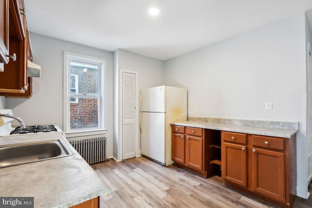 kitchen featuring radiator, sink, exhaust hood, white fridge, and light wood-type flooring