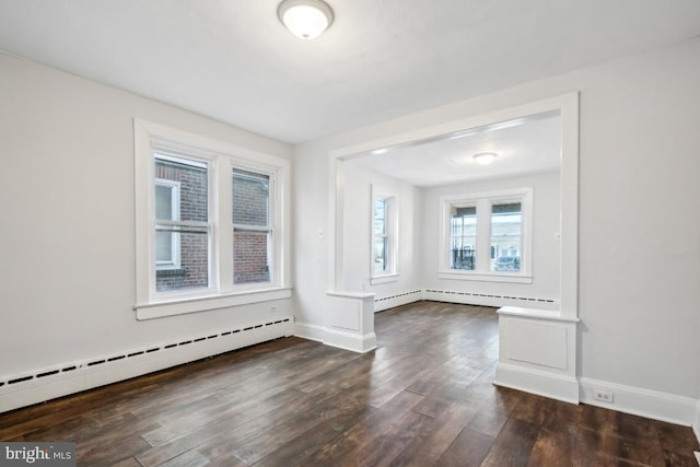 empty room featuring a baseboard heating unit and dark hardwood / wood-style floors