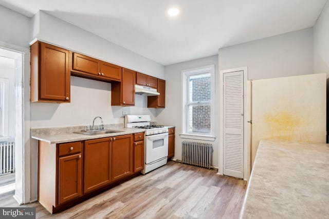 kitchen featuring light wood-type flooring, radiator heating unit, sink, and white gas range