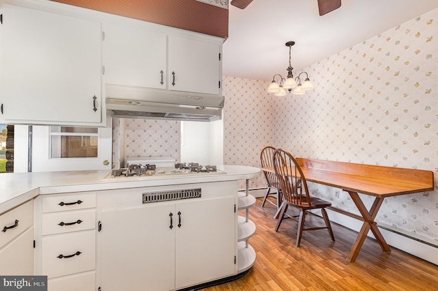 kitchen with light wood-type flooring, white gas stovetop, a notable chandelier, white cabinets, and hanging light fixtures