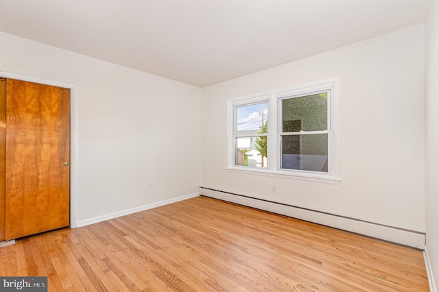 unfurnished room featuring light hardwood / wood-style flooring and baseboard heating